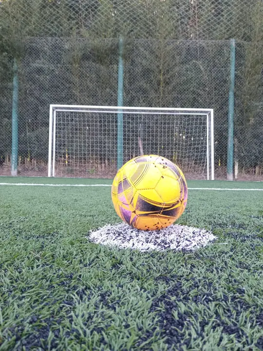 Pelota amarilla en el punto penal de la cancha de fútbol