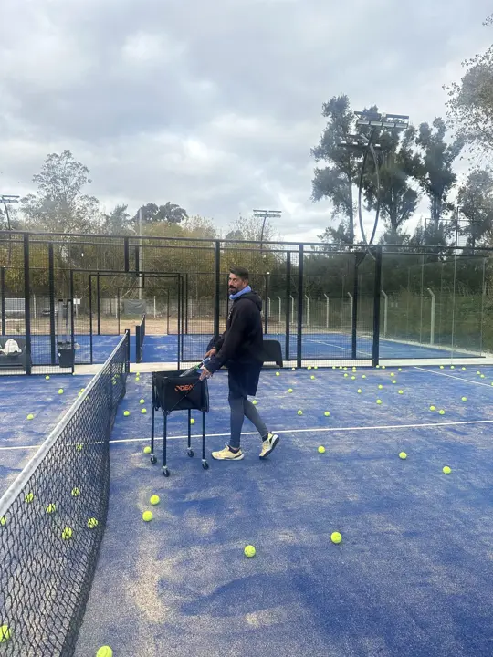 Profe con el carrito de pelotas en la cancha