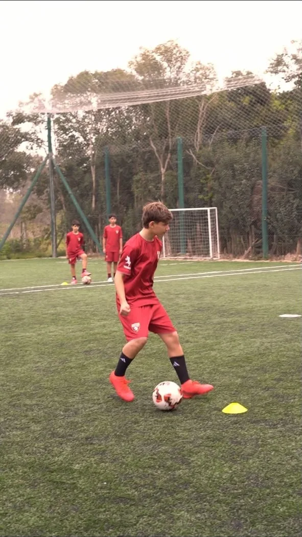 Un chico conduce la pelota entre conos