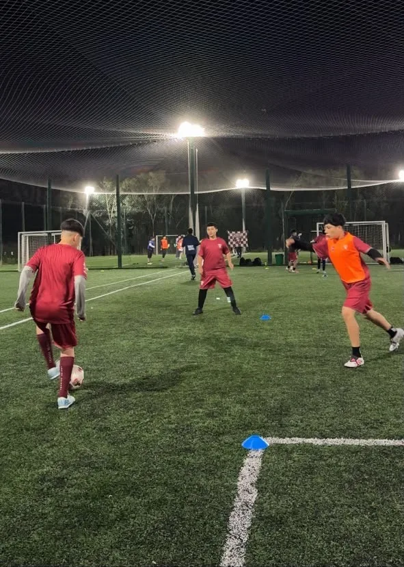 Chicos de Torino FC Academy entrenando de noche en una cancha de Champa