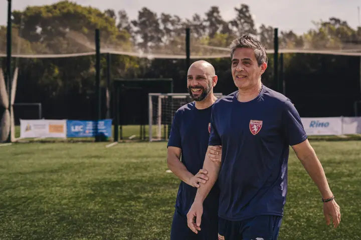 Dos entrenadores de la academia caminando por la cancha de Champa